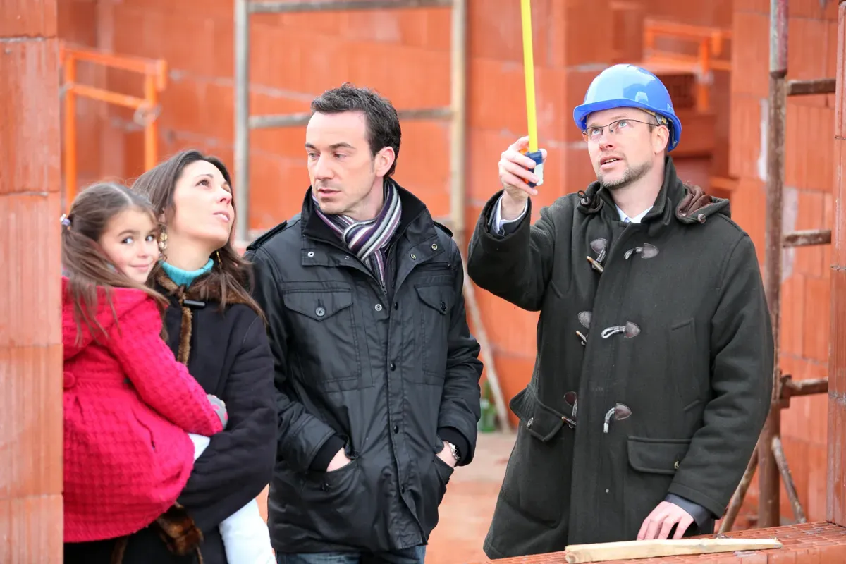 Contractor and clients reviewing architectural plans in a luxury renovation project management setting